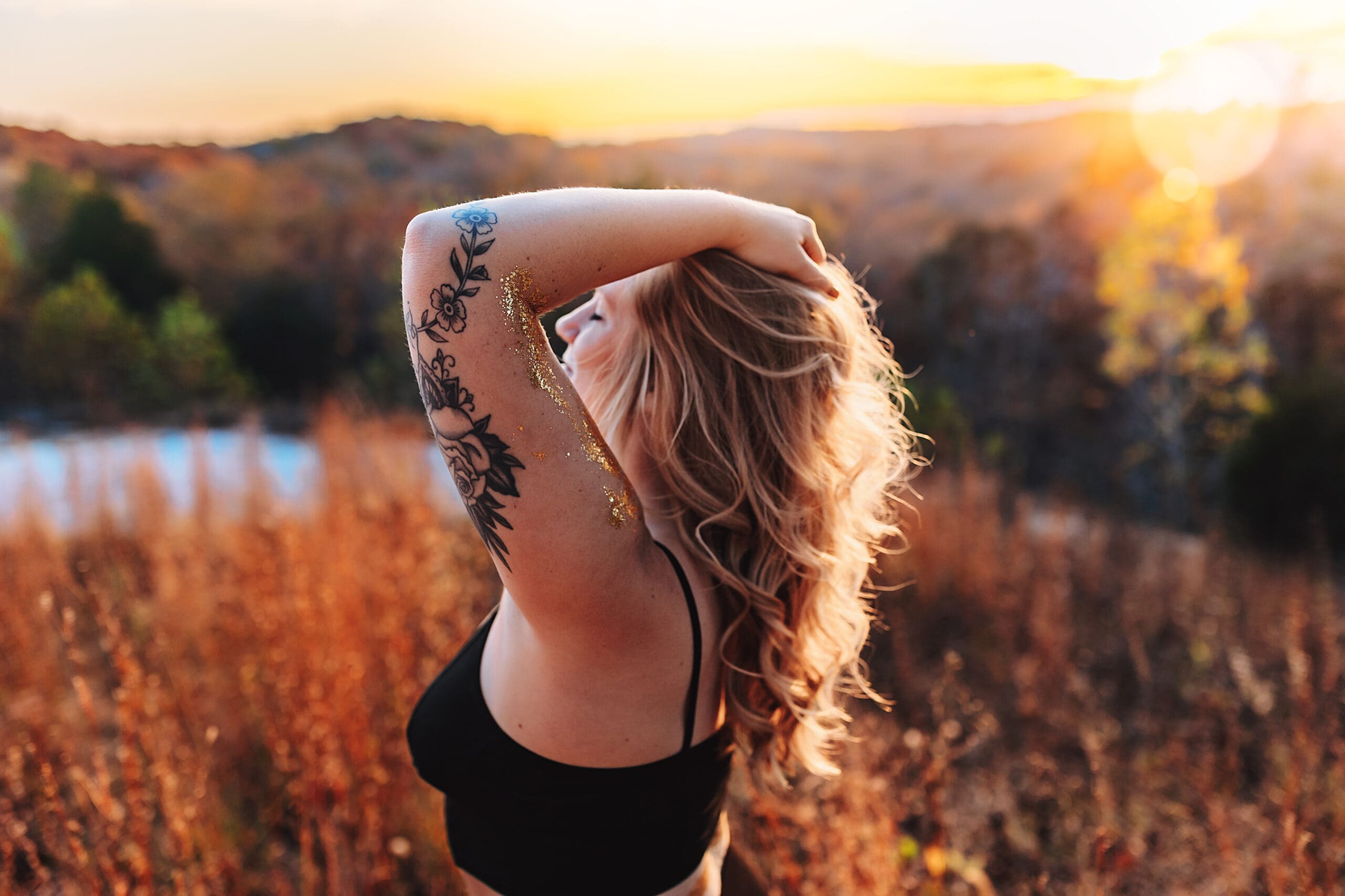 A woman standing in golden hour light, eyes closed, arm resting over her head — grounded, soft, and fully present in her body. This image represents the best kind of sexy: confidence rooted in peace, self-trust, and alignment rather than performance.